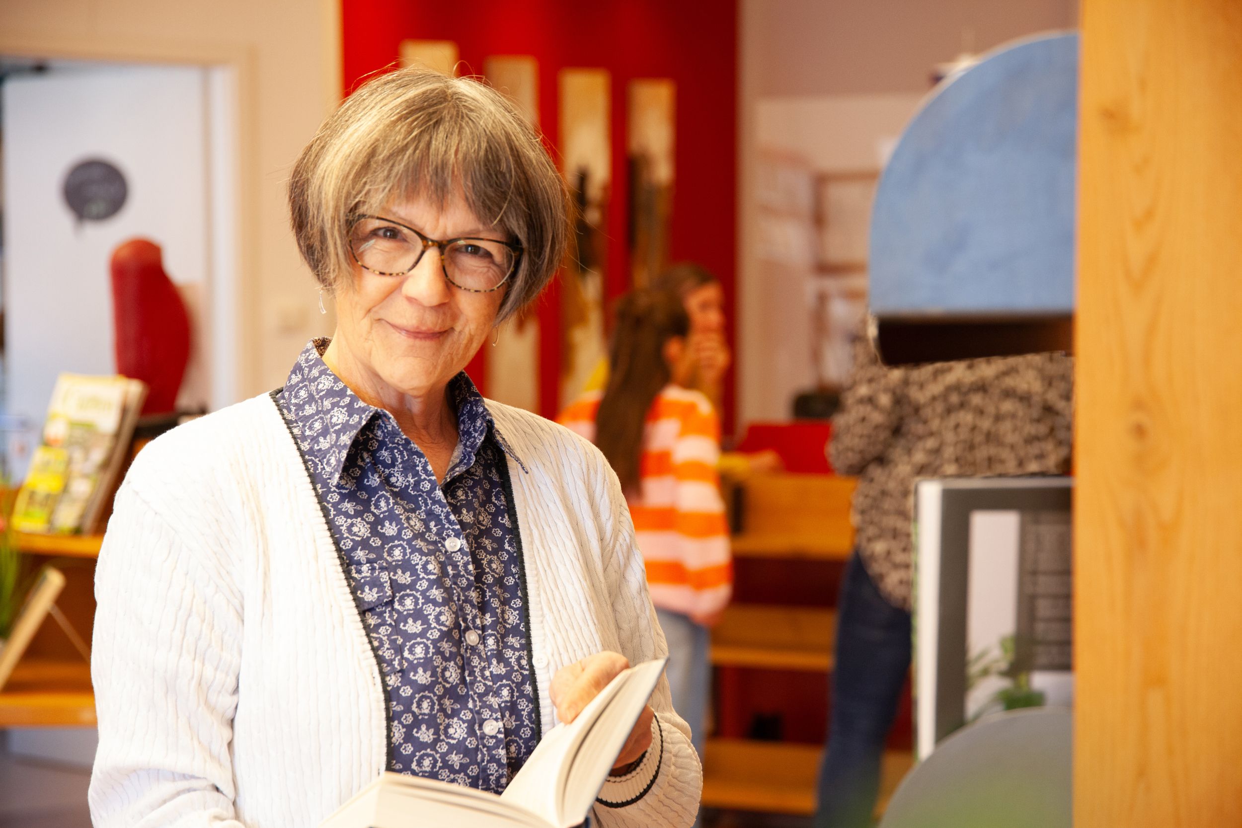 Eine Frau steht am Neuheitenregal und betrachtet ein neues Buch