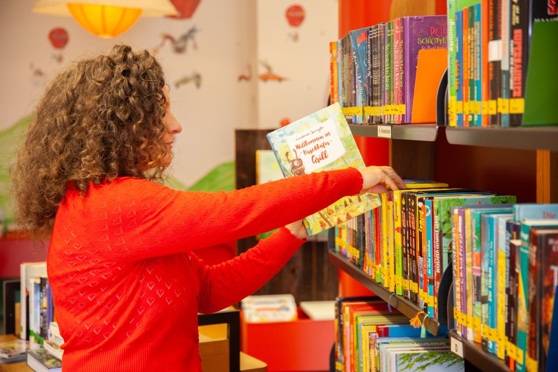 Mitarbeiterin sortiert Bücher in ein Bücherregal