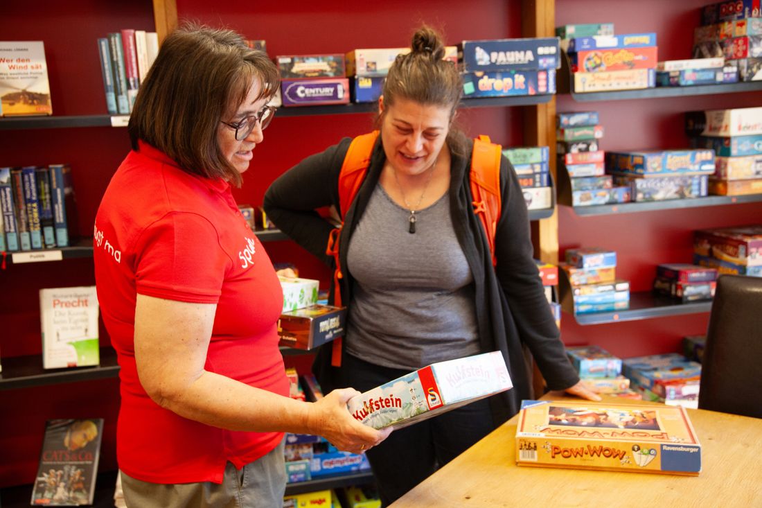 Mitarbeiterin erklärt Kundin ein Spiel