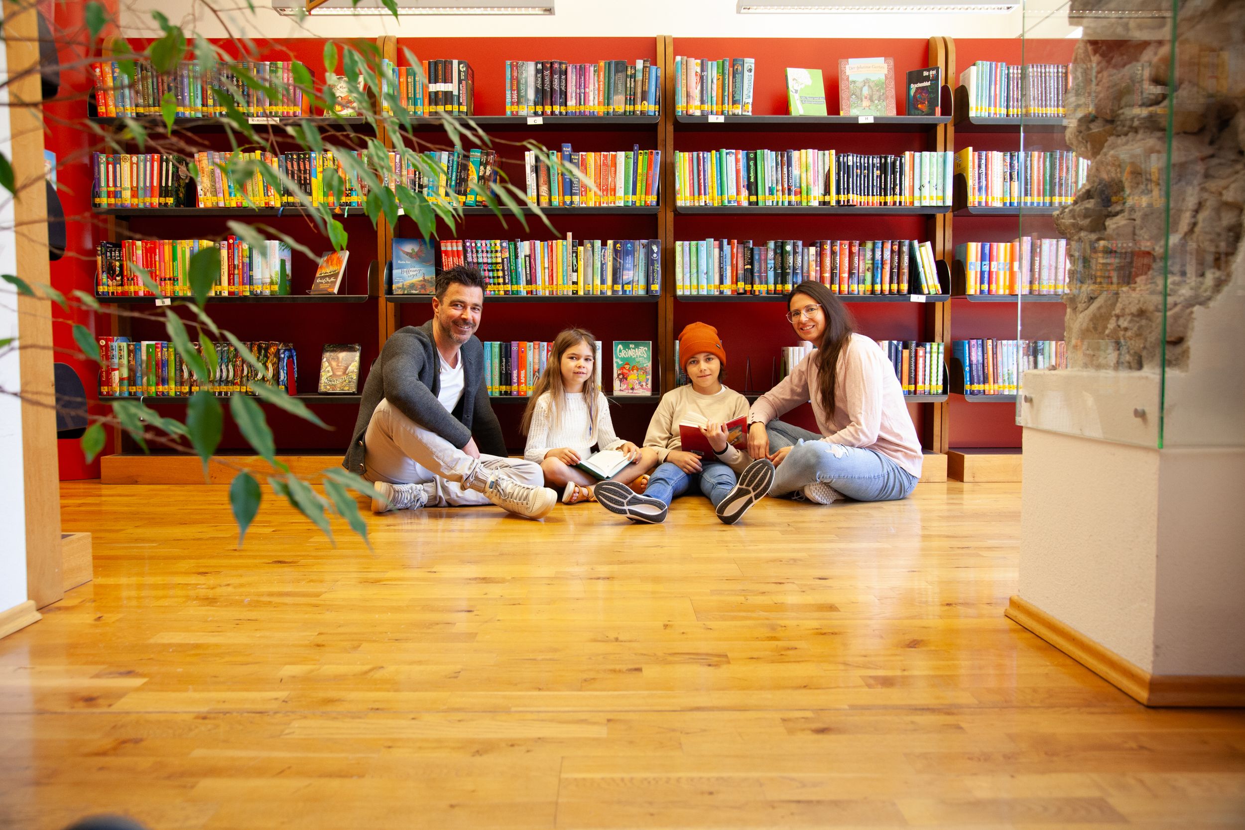Eine Familie sitzt vor Bücherregalen