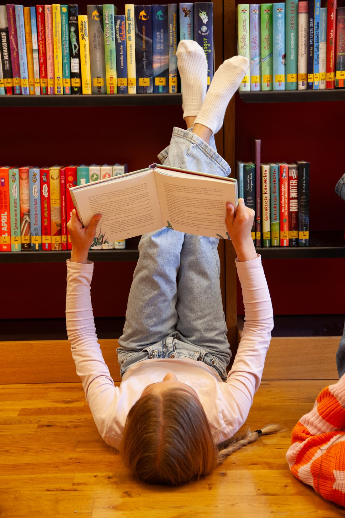 Mädchen mit Buch vor Kinderbuchregal