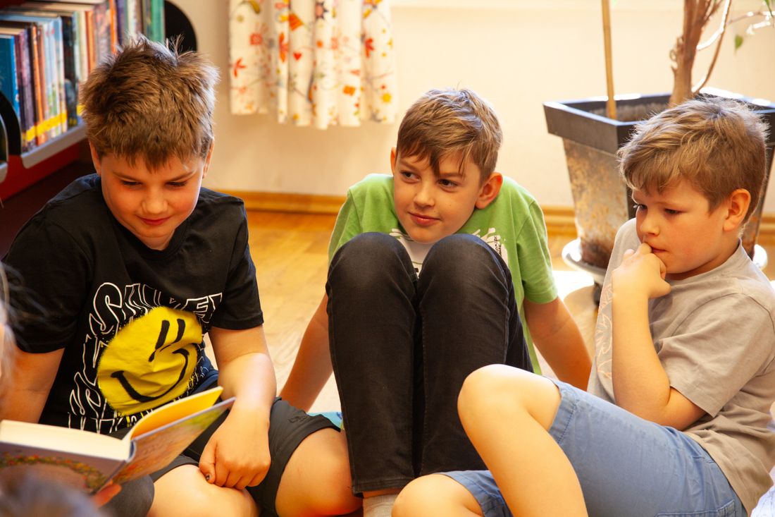 Drei Jungen hören interessiert zu.