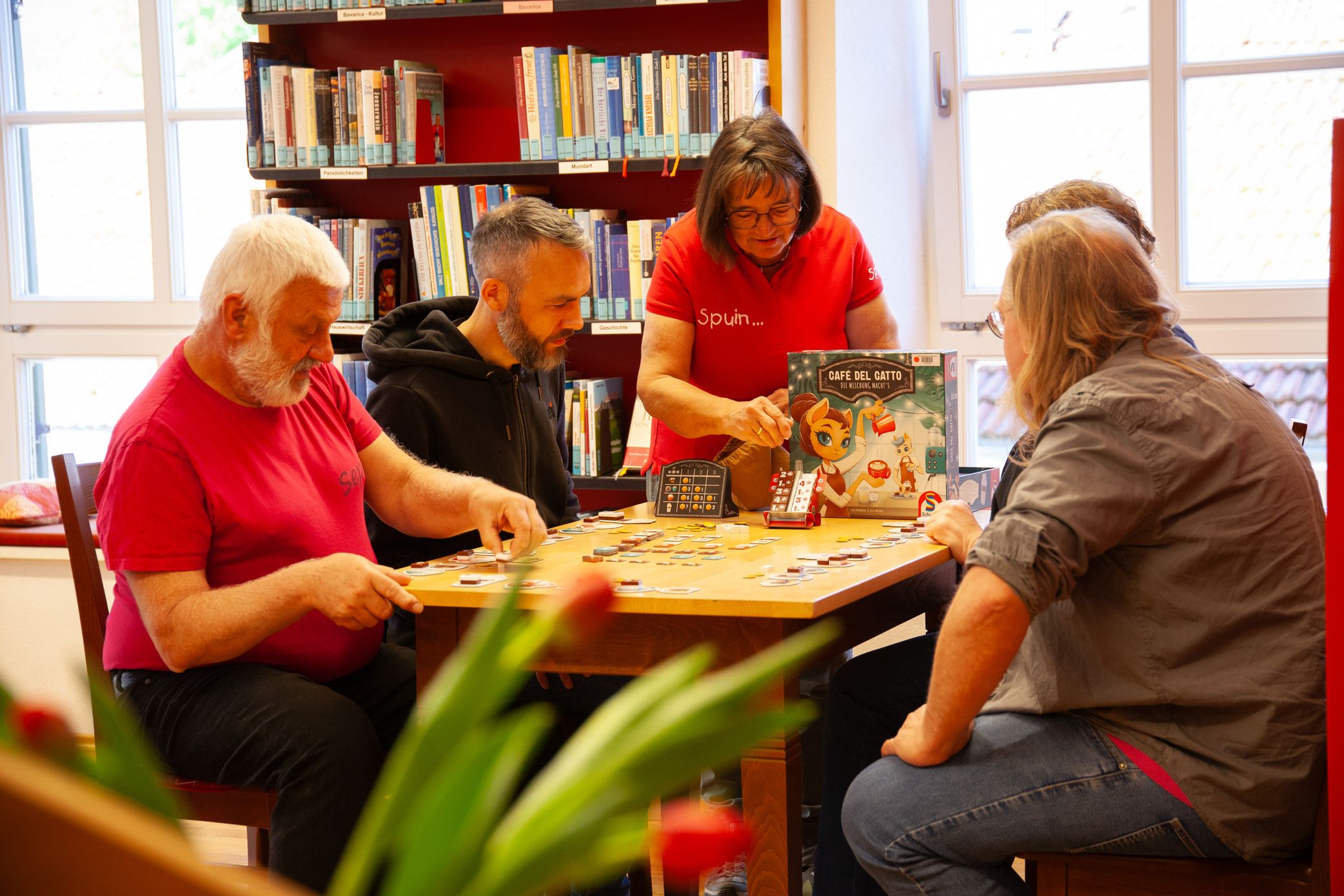 Mitarbeiterin der Bücherei Grassau erklärt anderen Spielern ein Spiel